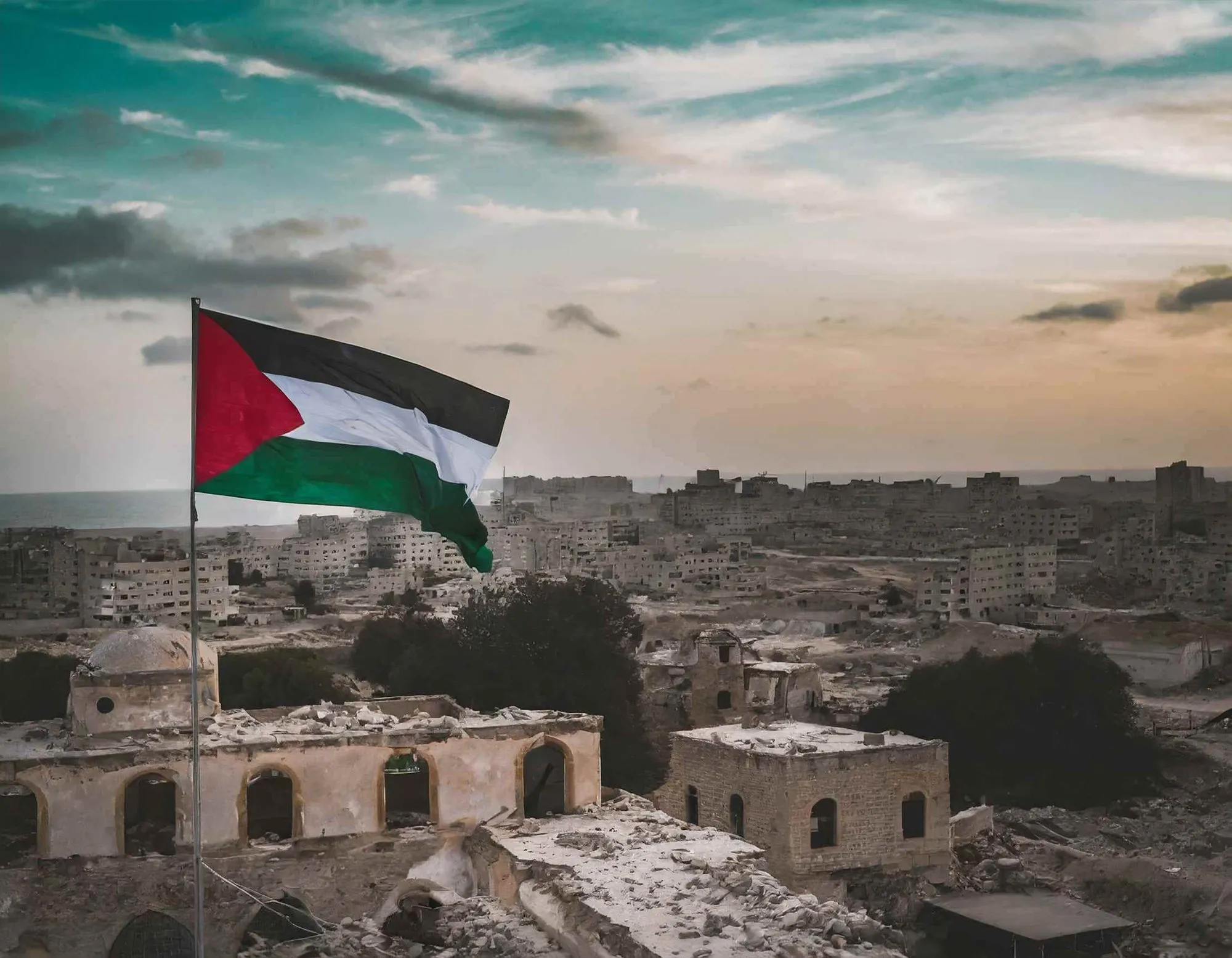 The flag of Palestine flying over a city at dusk